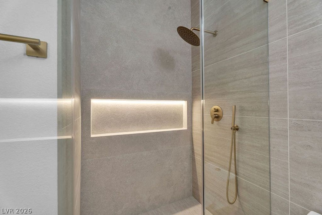 2690 Grassy Spring Place, Las Vegas, NV 89135 Textured tile walls and gold fixtures define this modern walk-in shower with integrated lighting.