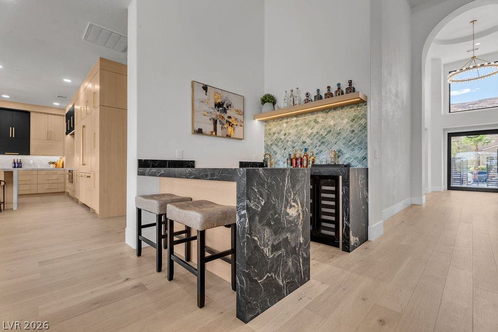 2690 Grassy Spring Place, Las Vegas, NV 89135 An elegant home bar features striking dark marble counters and light hardwood flooring.
