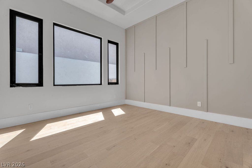 2690 Grassy Spring Place, Las Vegas, NV 89135 Clean lines and geometric wall detailing define this modern bedroom featuring light wood flooring.