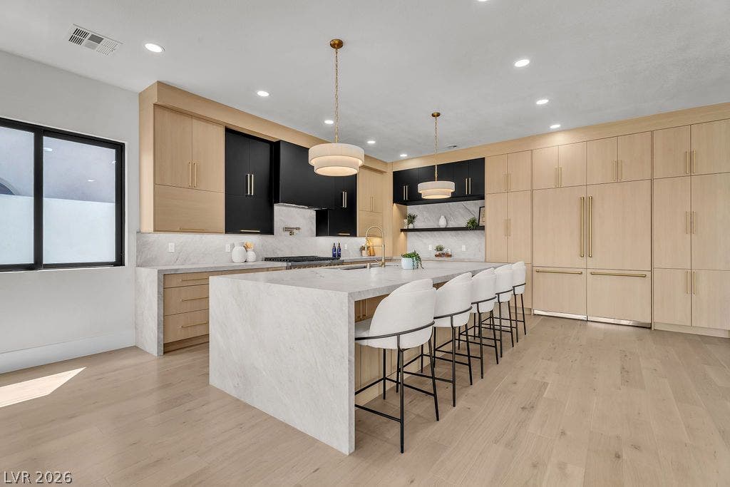 2690 Grassy Spring Place, Las Vegas, NV 89135 Custom light wood cabinetry and waterfall stone countertops define this modern kitchen space.