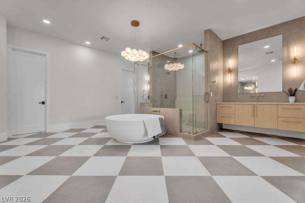 2690 Grassy Spring Place, Las Vegas, NV 89135 Geometric patterned tile floors anchor this contemporary bathroom featuring a freestanding tub and glass shower.