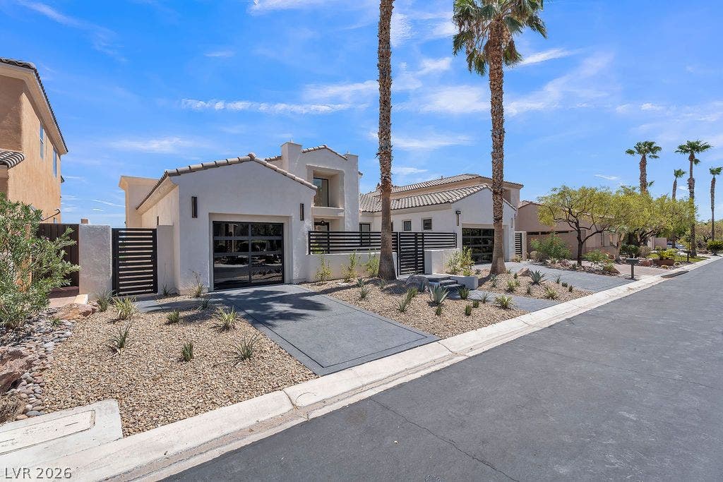 2690 Grassy Spring Place, Las Vegas, NV 89135 Palm trees frame the stucco exterior and modern glass garage doors of this contemporary desert home.