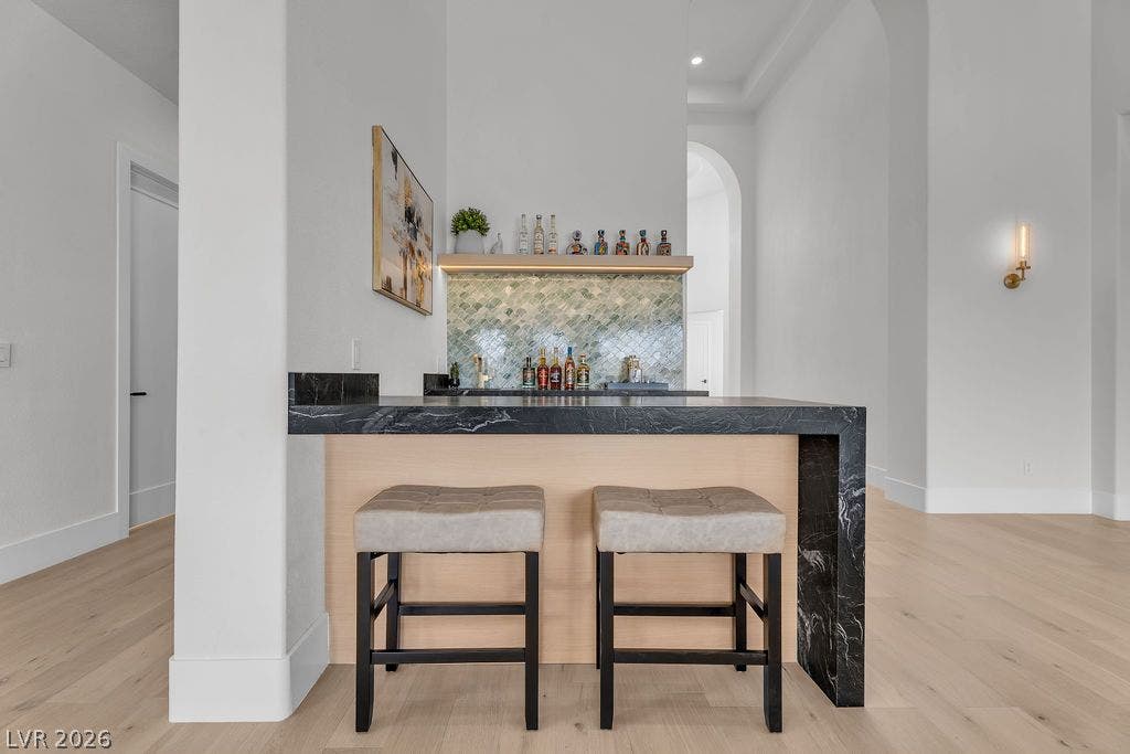 2690 Grassy Spring Place, Las Vegas, NV 89135 A stylish wet bar features a striking dark marble countertop and beautiful wood flooring.