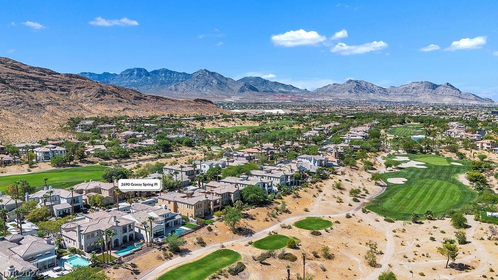 2690 Grassy Spring Place, Las Vegas, NV 89135 Dramatic mountain ranges frame a verdant golf course community under clear blue desert skies.