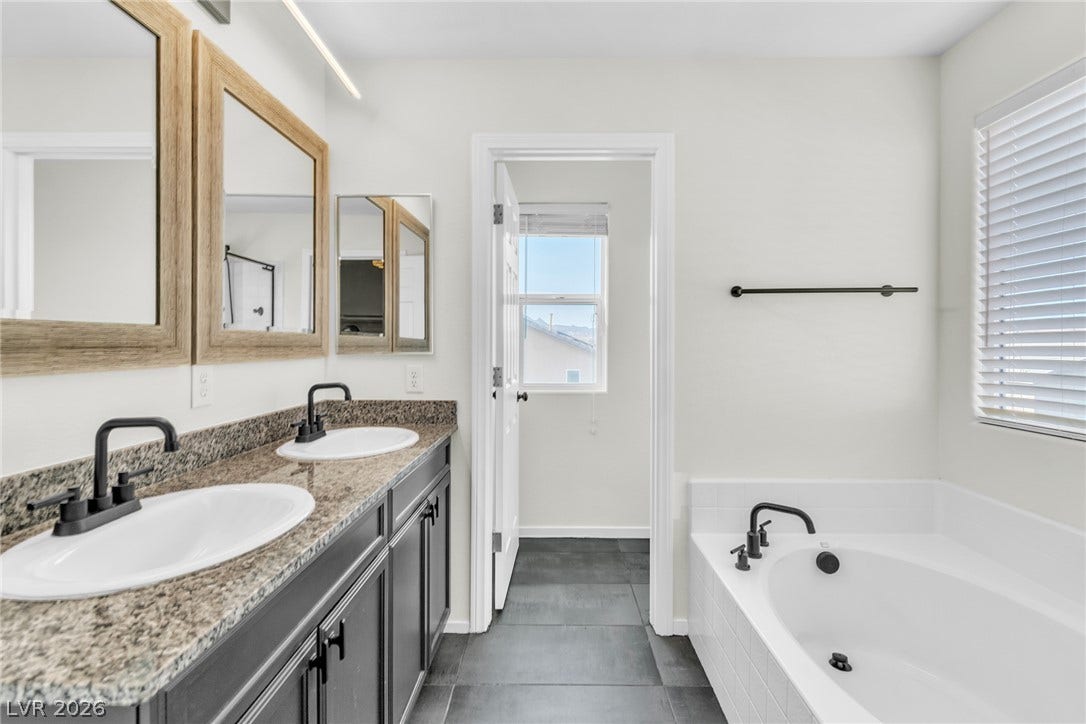 Double vanities with stone counters flank a soaking tub in this bathroom.