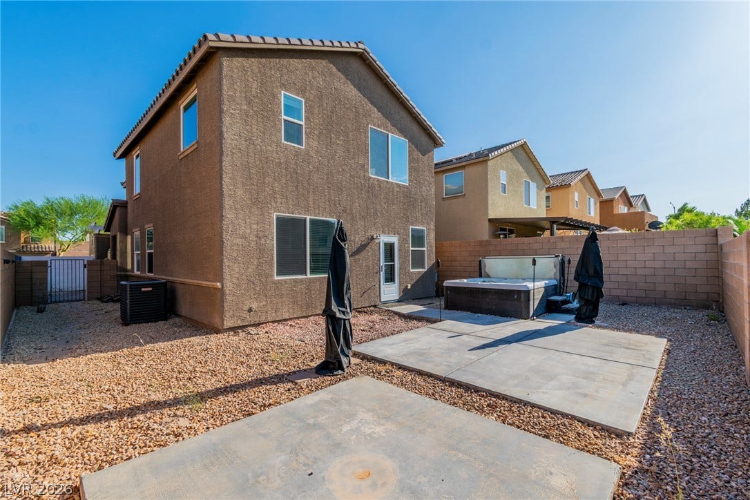 Concrete patio slabs and low-maintenance gravel surround a private backyard spa under clear desert skies.