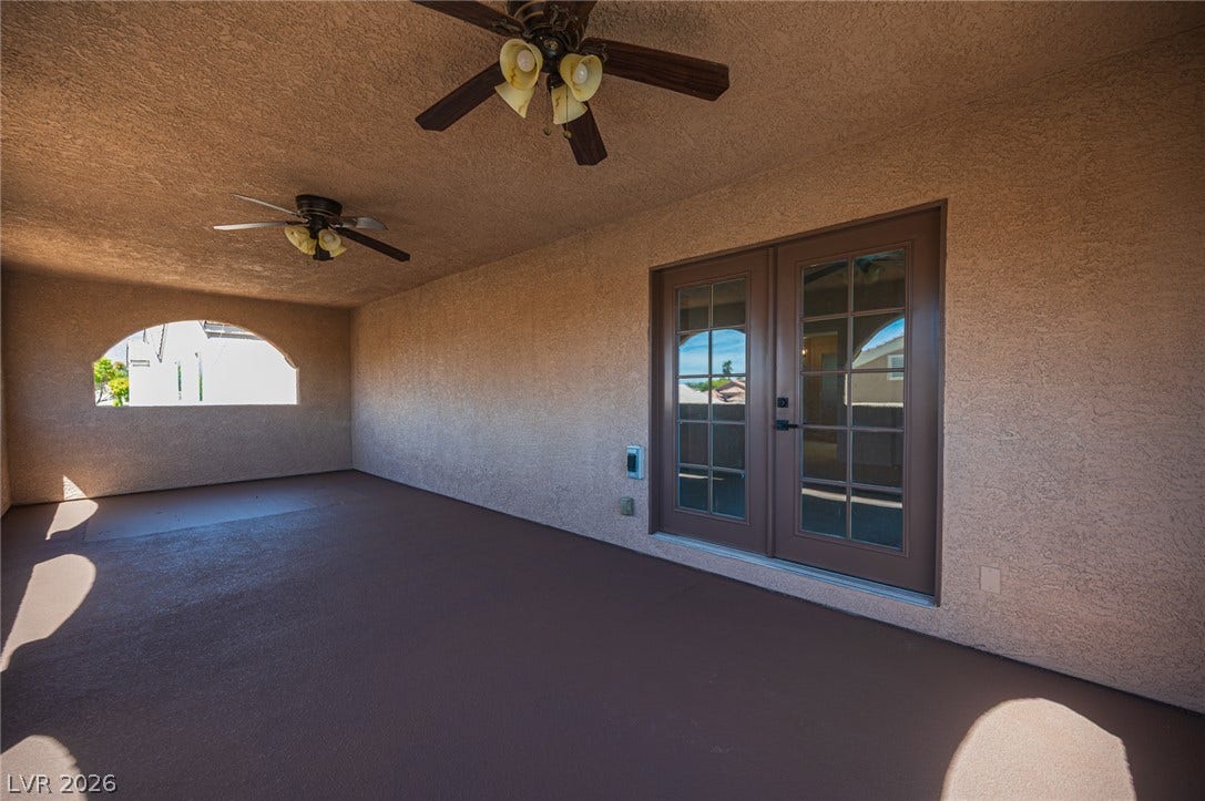 6133 Crystal Talon Street, Las Vegas, NV 89130 An arched opening and French doors define this covered outdoor patio space with stucco walls.