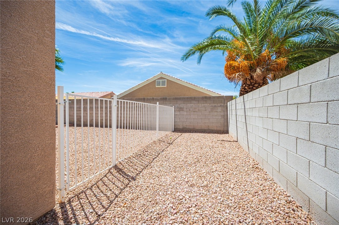 6133 Crystal Talon Street, Las Vegas, NV 89130 Stucco exterior walls and structural masonry fencing enclose a low-maintenance gravel yard.