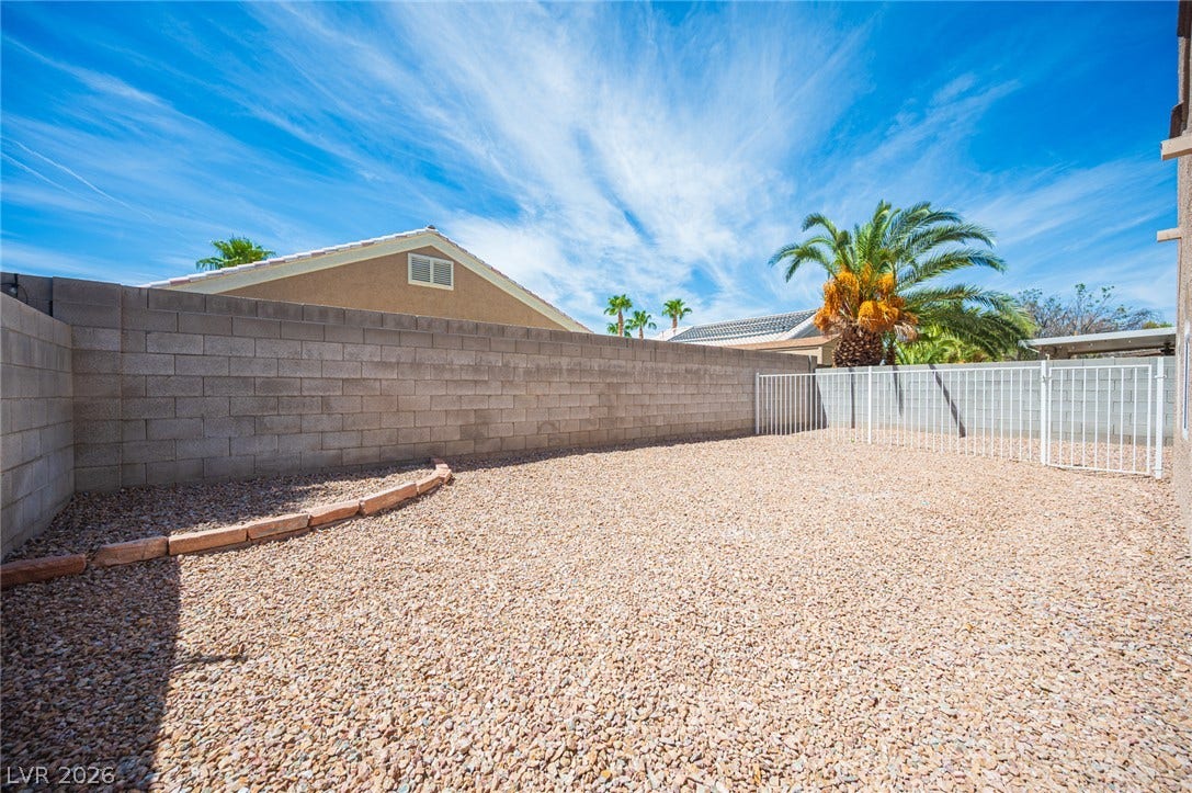 6133 Crystal Talon Street, Las Vegas, NV 89130 An enclosed gravel yard features concrete block walls and a white metal security gate.