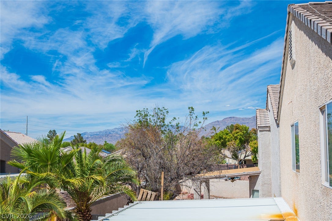 6133 Crystal Talon Street, Las Vegas, NV 89130 Distant mountain ranges rise behind the neighborhood trees under a blue sky.