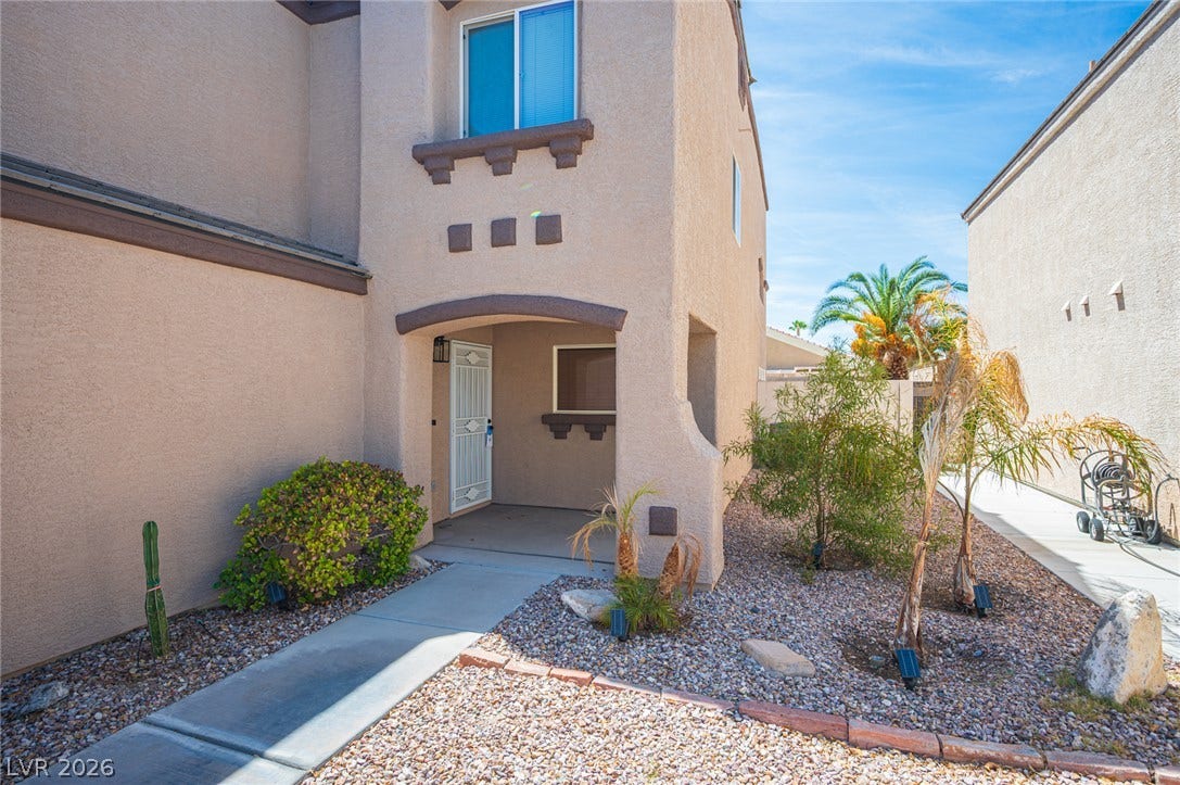 6133 Crystal Talon Street, Las Vegas, NV 89130 Concrete walkways lead to a recessed entryway featuring desert-friendly plantings and stucco architectural details.