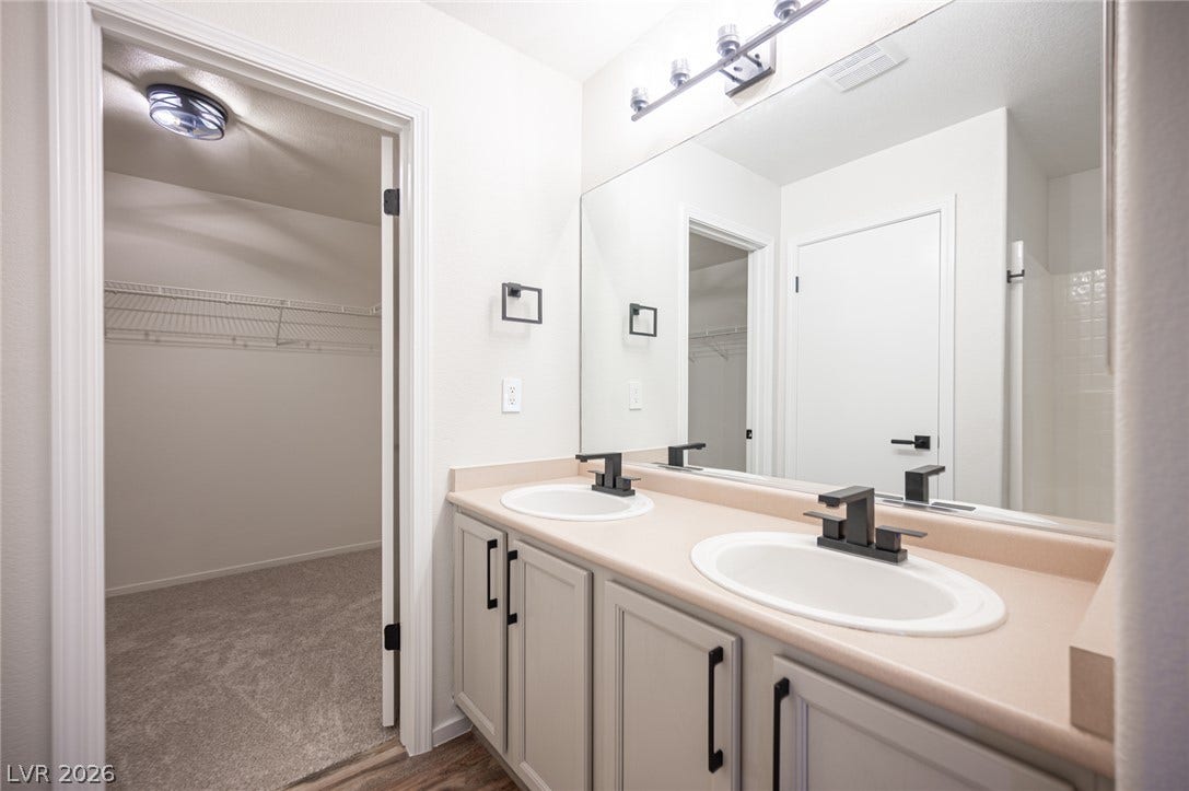 6133 Crystal Talon Street, Las Vegas, NV 89130 Clean lines and a double vanity define this functional bathroom adjoining a carpeted walk-in closet.