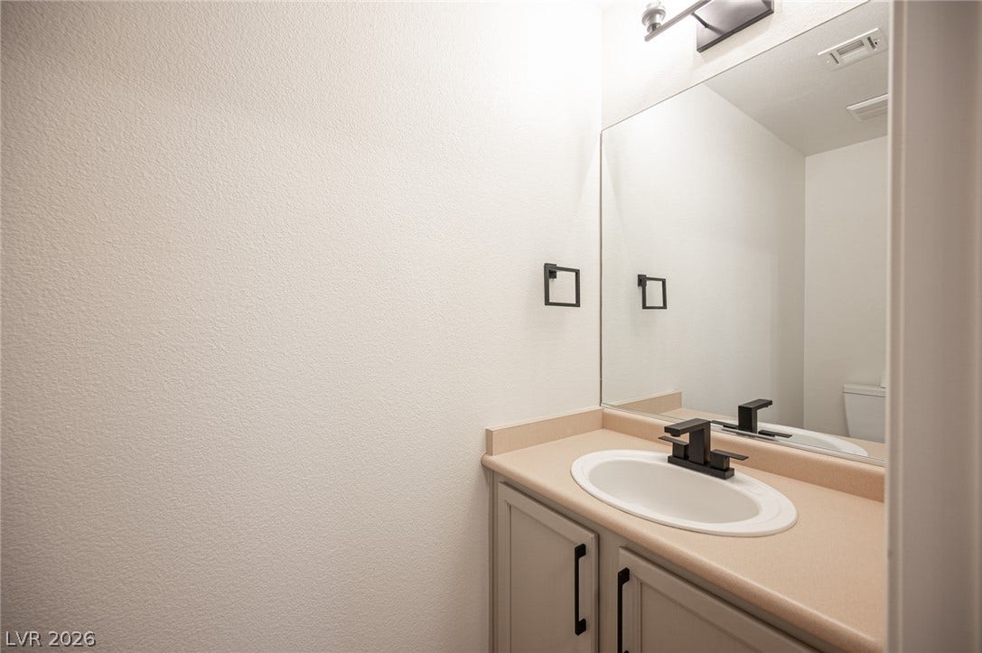 6133 Crystal Talon Street, Las Vegas, NV 89130 A minimalist vanity with clean lines and a large mirror anchors this downstairs powder room.