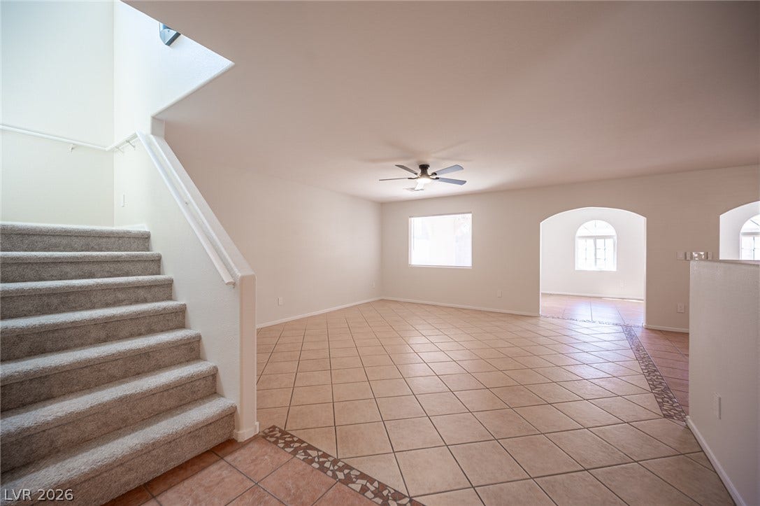 6133 Crystal Talon Street, Las Vegas, NV 89130 Tiled flooring and arched doorways define this versatile open living space adjacent to the carpeted staircase.