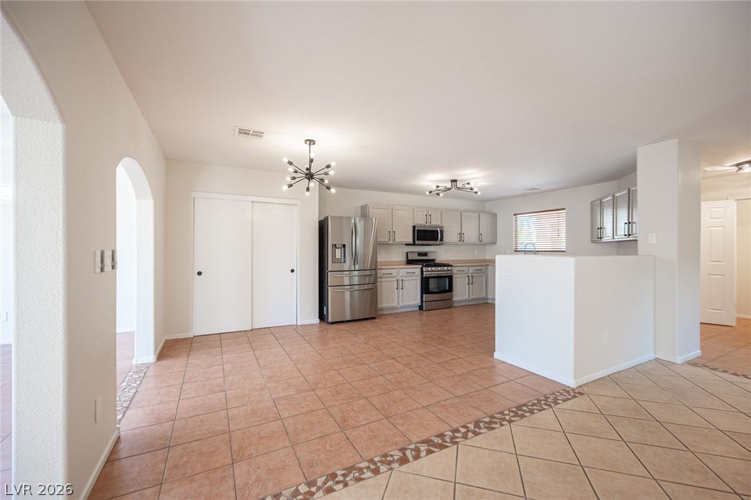 6133 Crystal Talon Street, Las Vegas, NV 89130 Tiled flooring and arched doorways lead into a kitchen with stainless steel appliances.
