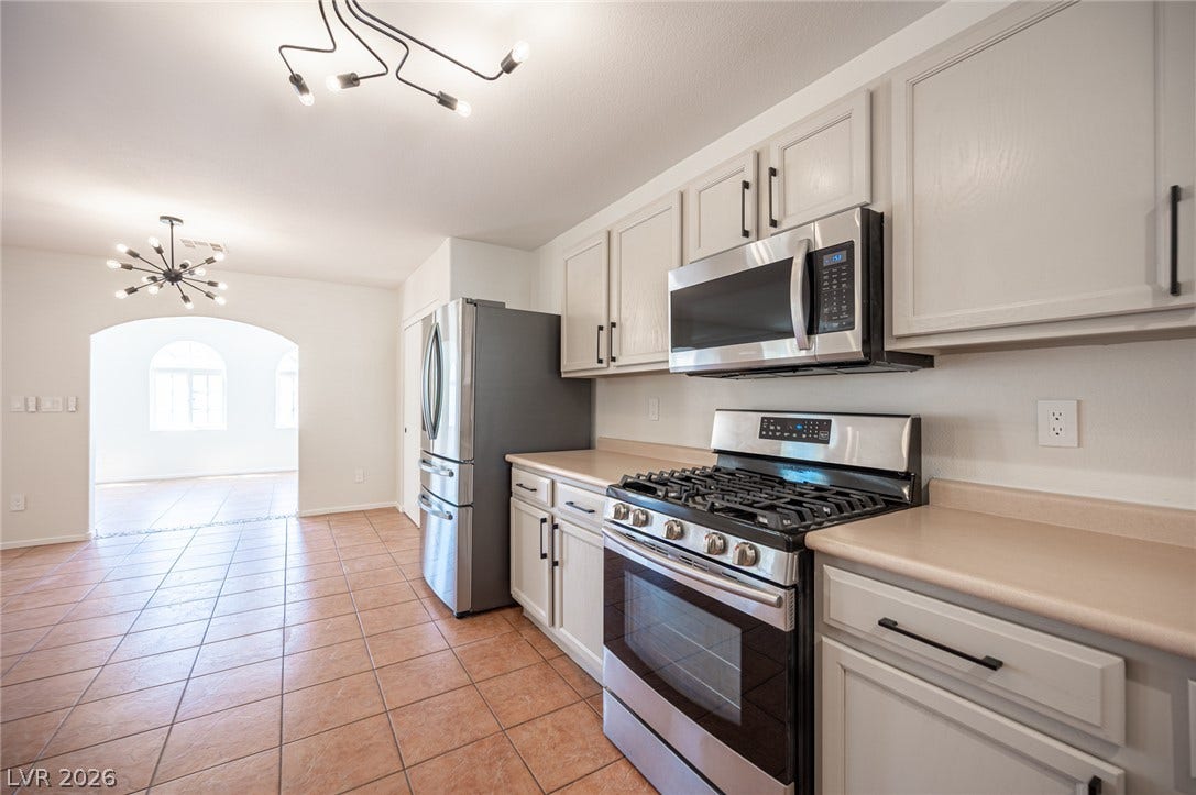 6133 Crystal Talon Street, Las Vegas, NV 89130 Tiled flooring flows through this kitchen equipped with stainless steel appliances and custom cabinetry.
