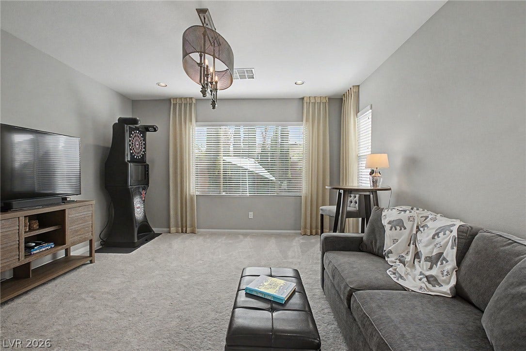 A spacious recreation room features plush neutral carpeting and recessed lighting.