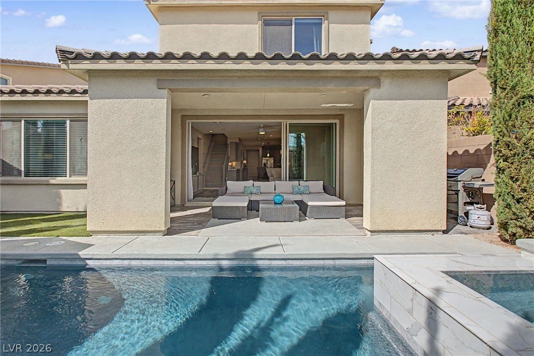An inviting backyard oasis features a glistening swimming pool bordering a covered patio structure.