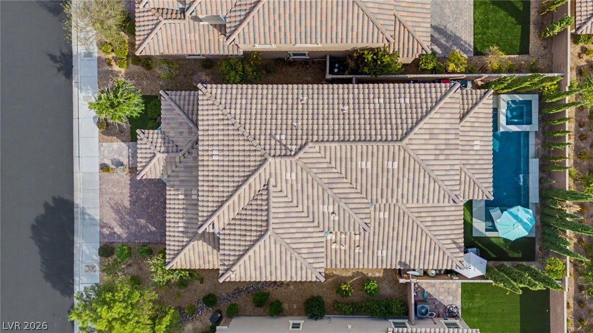 An aerial perspective showcases the tiled rooflines, backyard pool, and manicured landscaping of the property.