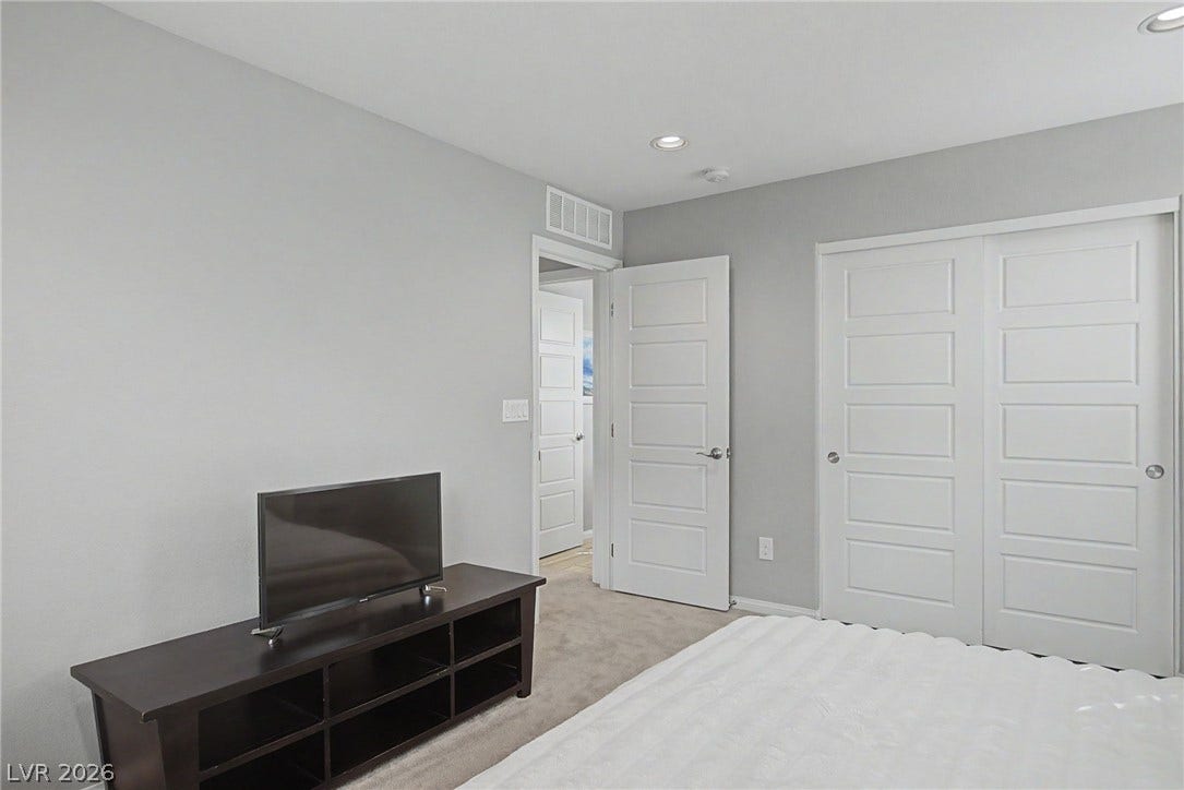Recessed lighting highlights plush carpet and clean modern walls in this serene space.