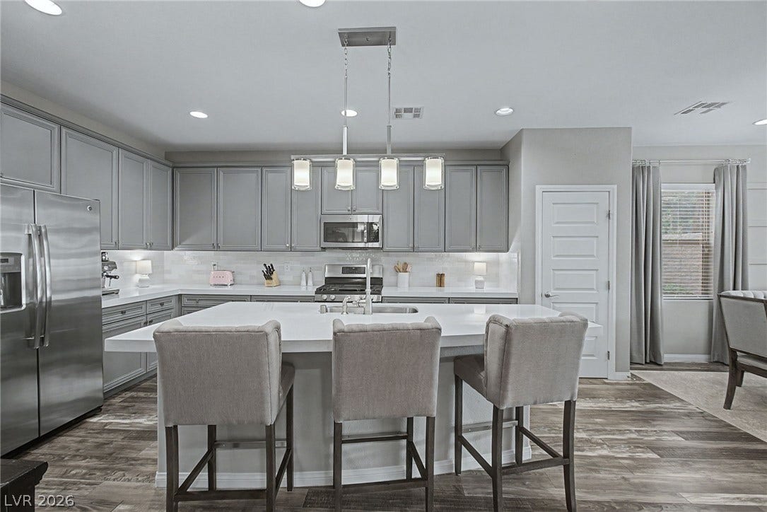 Sleek quartz countertops pair perfectly with shaker cabinetry and modern hard-surface flooring.