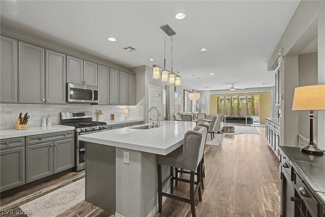 Hardwood floors and clean stone countertops define this open-concept culinary space.