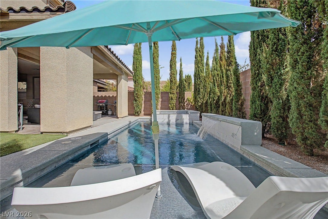 Mature perimeter trees frame a geometric swimming pool complete with an integrated stone waterfall feature.