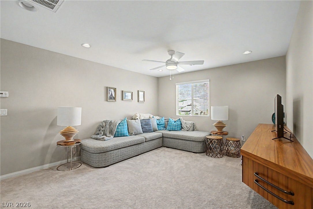 Recessed lighting and soft wall tones create a comfortable atmosphere across this plush carpeted space.
