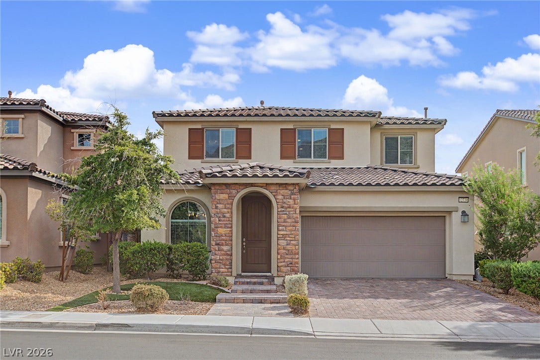 Stone accents and a tiled roof complement the handsome stucco exterior of this two-story home.