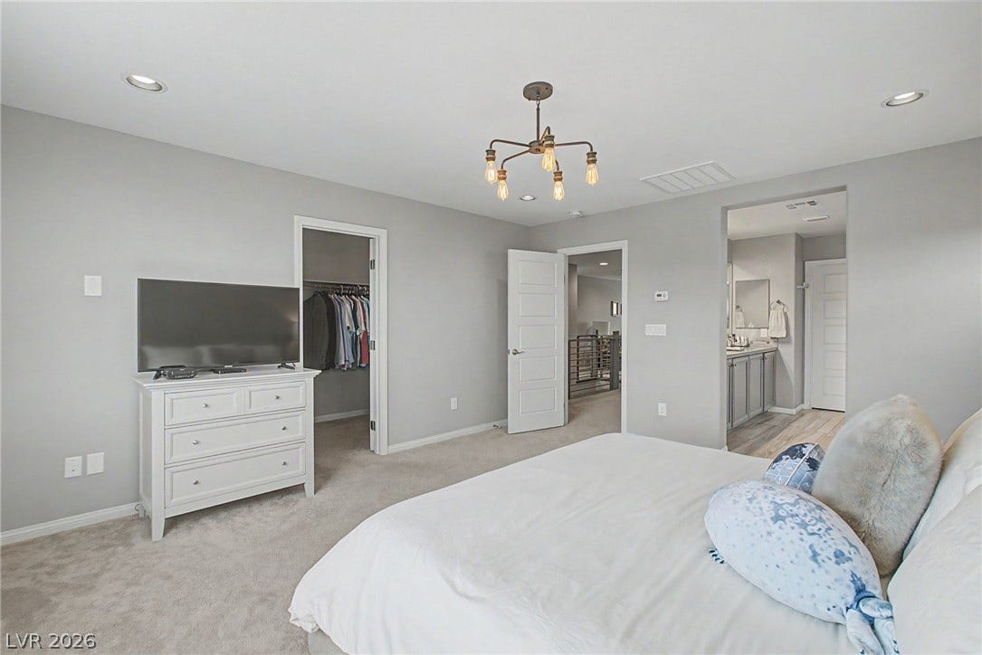 A spacious bedroom features neutral carpet and recessed lighting with direct access to a private bathroom.