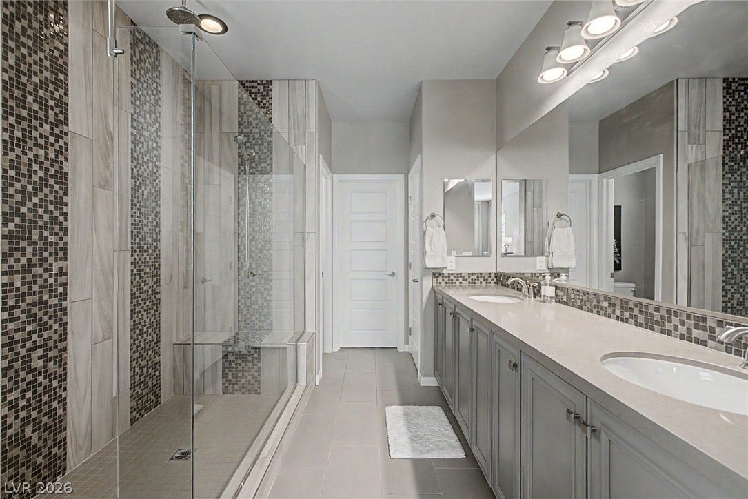 Clean lines and custom tilework define this modern bathroom with a double vanity.