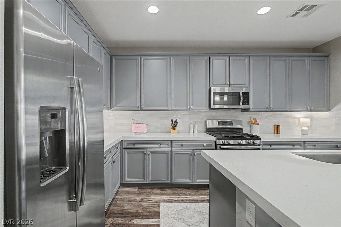 Sleek stone countertops complement classic cabinetry and modern stainless steel appliances in this updated space.