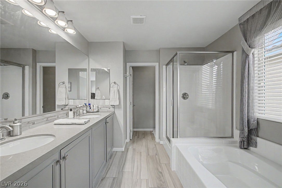 Double vanities, a glass-enclosed shower, and a soaking tub define this modern bathroom space.