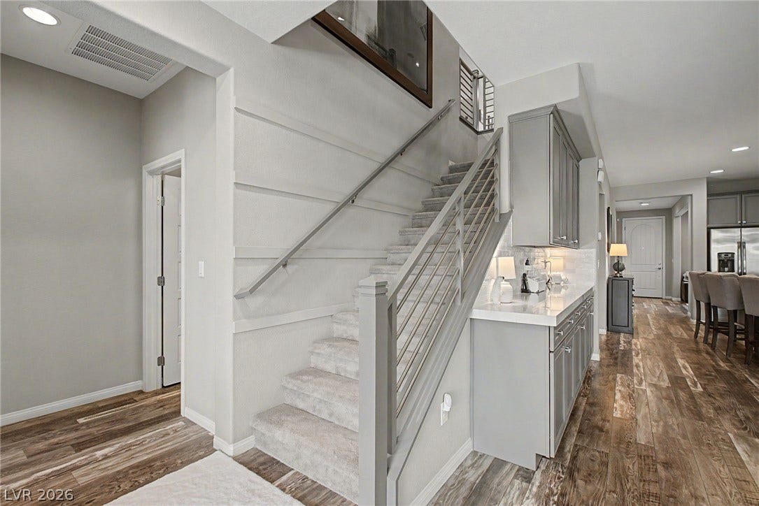 Rich wood-look flooring and a modern open staircase with metal railings anchor this versatile entryway.