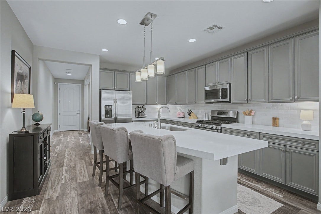Recessed lighting illuminates wood-look flooring and structured cabinetry in a modern kitchen space.