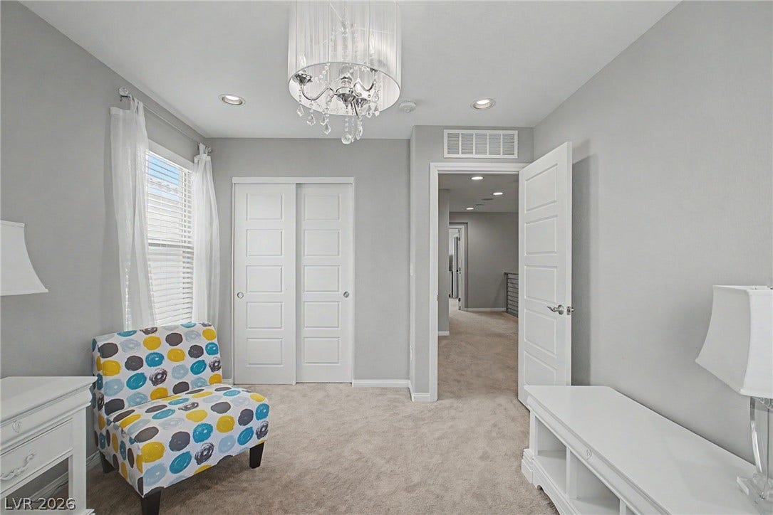 Recessed lighting and a stylish chandelier illuminate this cozy space with wall-to-wall carpeting.