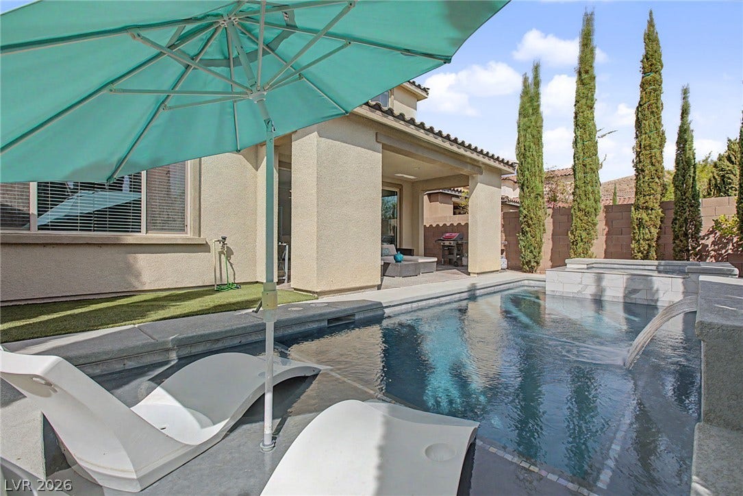 Manicured cypress trees line the private backyard pool area complete with integrated waterfall and spa.