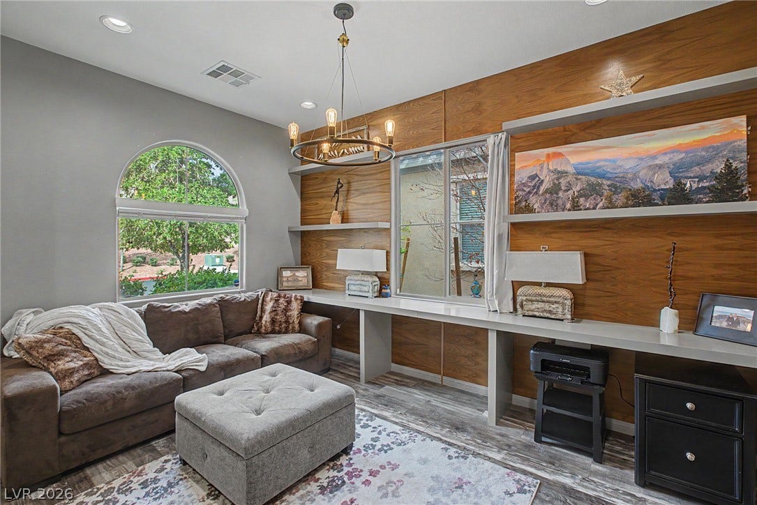 Rich wood paneling and integrated floating shelving anchor this versatile living space.