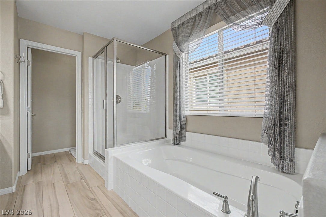 A deep soaking tub sits adjacent to a glass-enclosed shower on tile flooring.