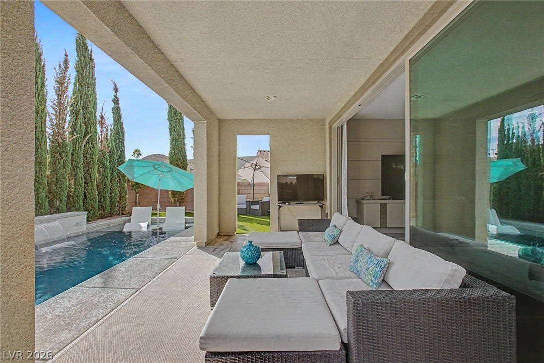 Sliding glass doors connect the interior spaces to a covered patio overlooking the private pool.