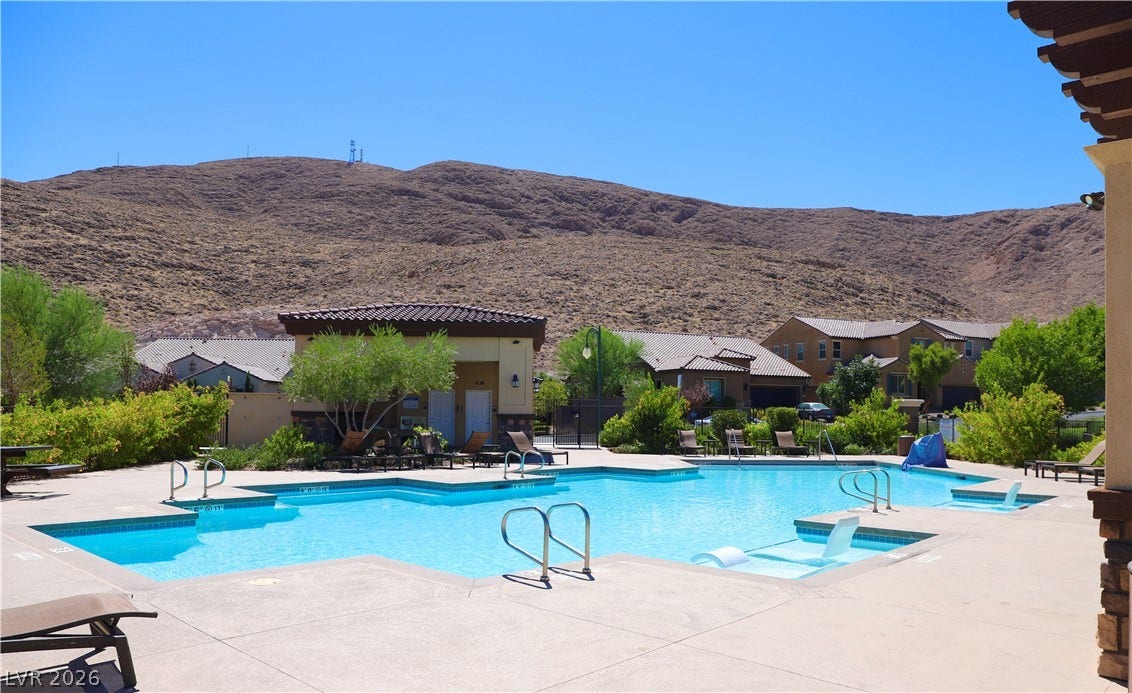 An inviting community swimming pool sits framed by dramatic desert mountain vistas.