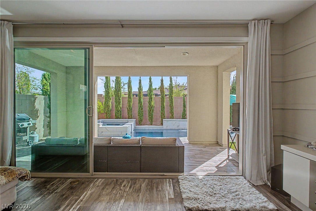 Sliding doors bridge indoor living spaces with a covered patio and private backyard pool.