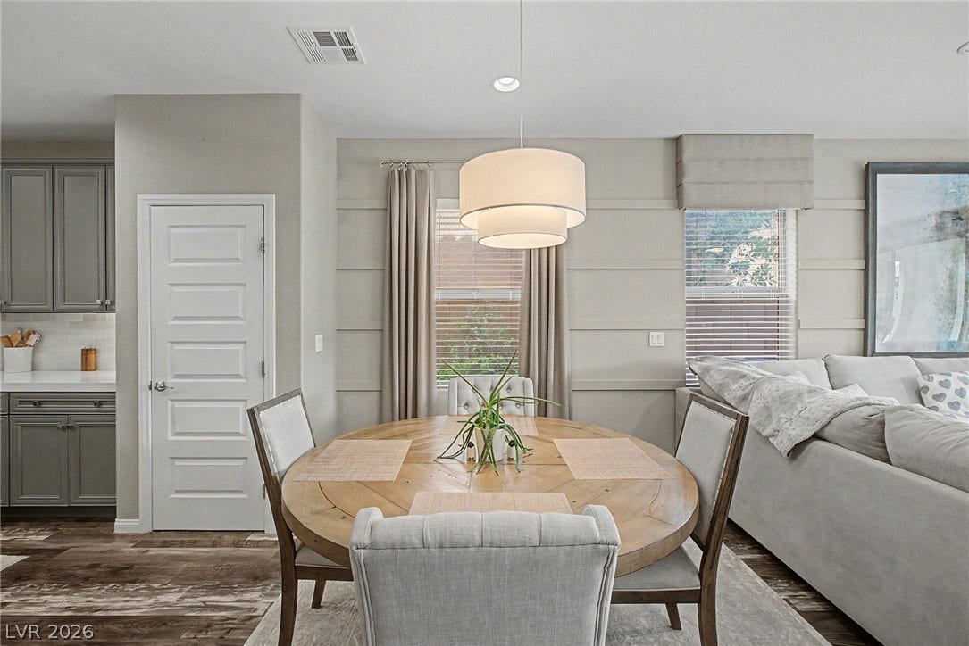 A light-filled dining space integrates with the kitchen and living area over rich wood-look flooring.