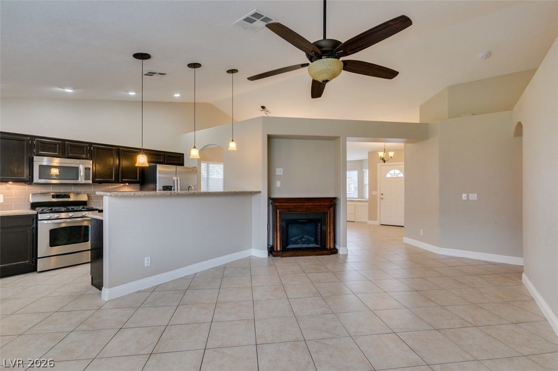 437 Waterwheel Falls Drive, Henderson, NV 89015 An open living space features tiled floors, high ceilings, and a fireplace beside the kitchen.