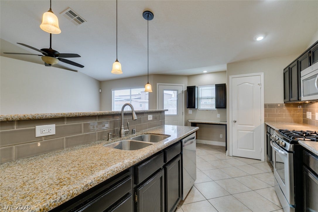 437 Waterwheel Falls Drive, Henderson, NV 89015 Polished stone countertops and sleek dark cabinetry accent this functional kitchen design.