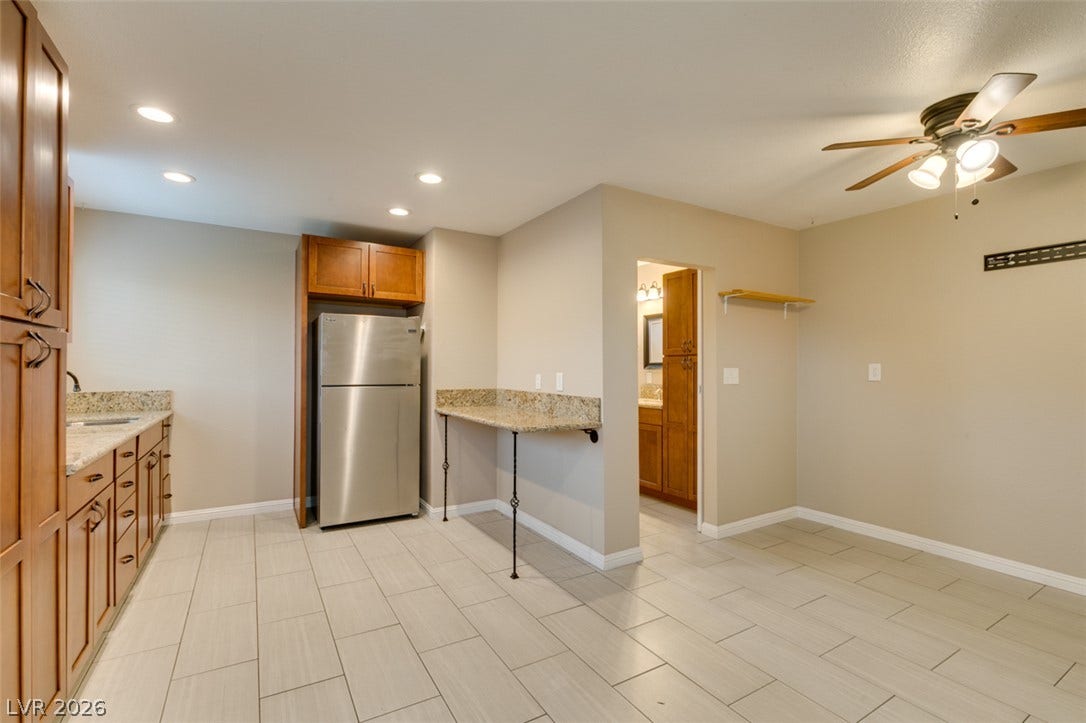 437 Waterwheel Falls Drive, Henderson, NV 89015 Guest house kitchen. Ample wooden cabinetry and stone countertops anchor this functional cooking and dining space.
