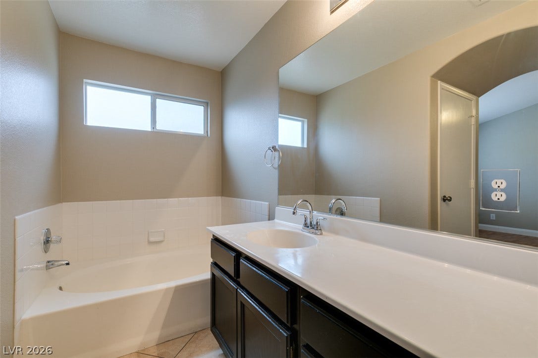 437 Waterwheel Falls Drive, Henderson, NV 89015 A deep soaking tub sits adjacent to a dark vanity with a large wall mirror.