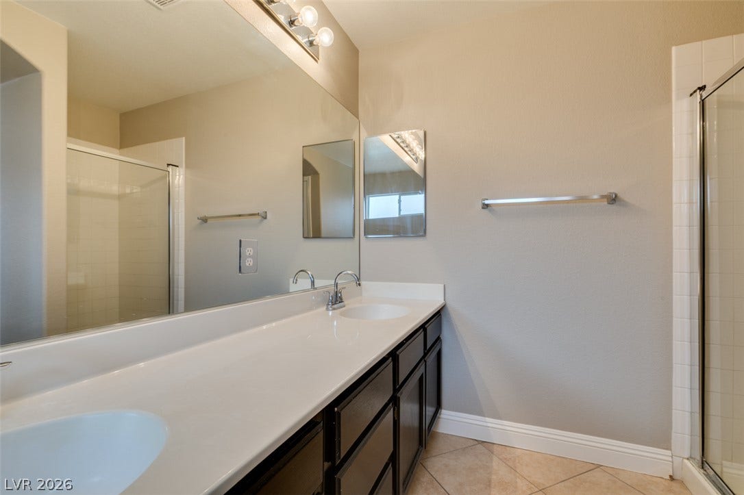 437 Waterwheel Falls Drive, Henderson, NV 89015 Clean-lined bathroom features tiled flooring alongside a long vanity and glass-enclosed shower.
