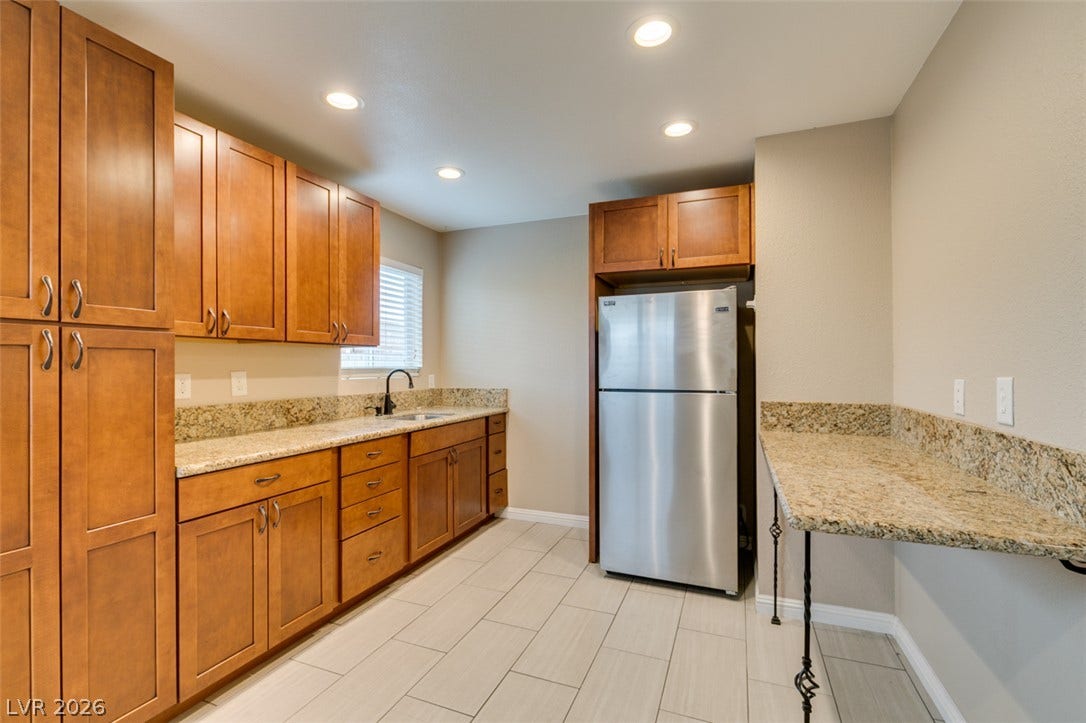 437 Waterwheel Falls Drive, Henderson, NV 89015 Polished stone countertops complement warm wood cabinetry in this well-appointed culinary space.