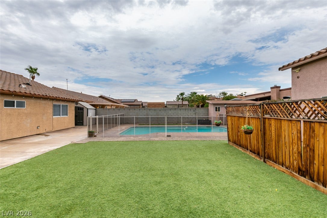 437 Waterwheel Falls Drive, Henderson, NV 89015 An inviting backyard features a tidy green lawn area alongside a gated swimming pool.